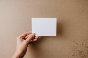 Hand holds a blank white card against a textured cardboard surface, focusing on versatility photo