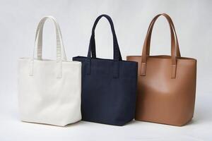 Three fabric tote bags in white, navy, and beige stand aligned on white photo