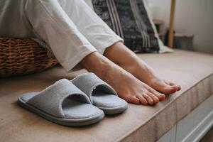 Feet rest on wicker basket, fuzzy slippers beside, cozy interior setting photo