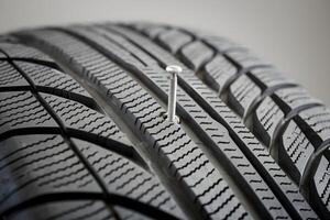 Close up of tire with distinct ridges, silver screw embedded in groove photo