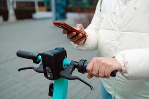 Handsome man using smartphone app. Guy approaches an electric scooter and using mobile phone app NFC contactless locker on bike bicycle in sharing parking lot. photo