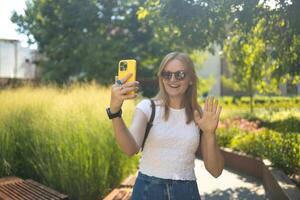Cheerful smiling 30s lady taking selfie outdoors in city park, happy young female capturing self-portrait while enjoying walk and good day, resting outside photo