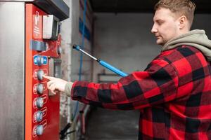 Close up of a hand pressing a button on a self-service coin machine at car wash. photo