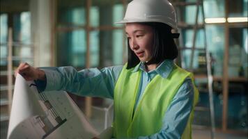 Asian girl architect Chinese engineer inspector developer looking at building plan check blueprint construction project own business startup Korean Japanese woman industry worker in hard hat smiling video
