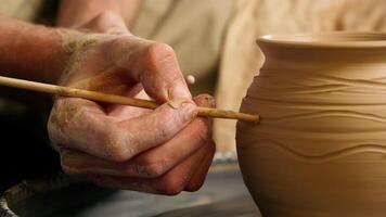 Close up unknown man master craftsman holding using modeling tool making decoration patterns clay pottery jug vase pot potter craft artisan hobby handcraft male artwork earthenware skilled workshop video
