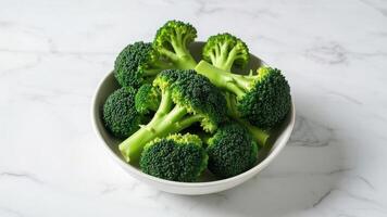 A bowl of fresh broccoli florets as a nutrient dense vegetable on white background. photo