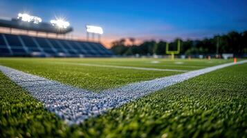 Football stadium field at night with illuminated bleachers and goal post photo