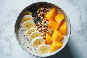 Smoothie bowl with sliced banana, mango, granola and chia seeds creating a healthy breakfast photo