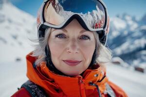 Portrait of smiling senior skier wearing ski helmet and goggles in mountains photo