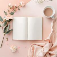 Open notebook, flowers and cup of coffee on pink background photo