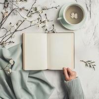 Woman's hands holding open notebook and cup of coffee on marble table photo