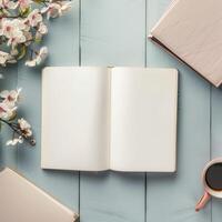 An open book, coffee and flowers on a blue wooden table photo
