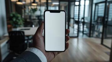 A man holding an iphone x mockup in an office photo