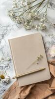 Blank notebook, pen and flowers on marble background photo