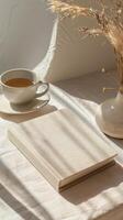 A book, a cup of tea and a vase of dried grass on a white bed photo