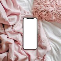 A smartphone is laying on a bed with a pink blanket photo