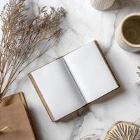 An open book, a cup of coffee and a vase of dried flowers on a marble table photo