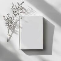 Blank white notebook with a branch on a white surface photo