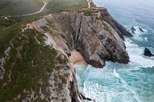 Drone view of huge rocky cliffs on seaside at beach during daytime photo