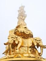 a golden statue of a buddha sitting on top of elephants photo