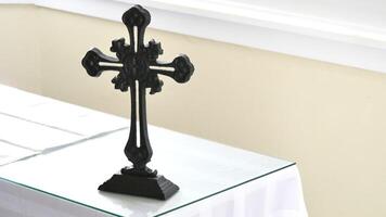 a black cross on a table in front of a window photo