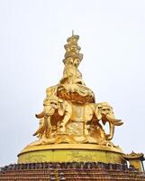 a golden statue of buddha on an elephant on top of a building photo