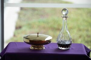 a wine decanter and a gold bowl on a purple table photo