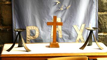a cross and two candles on a table in front of a banner photo