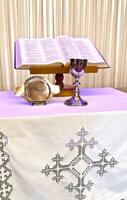a table with a silver chalice and an open bible photo
