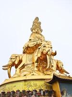 a golden statue of buddha sitting on top of a large elephant photo