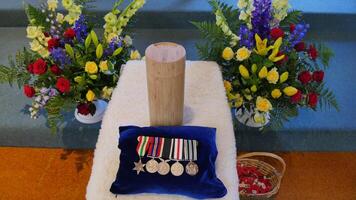 a wooden cross with medals and flowers on it photo