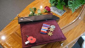 a casket with a medal, flowers and a ribbon photo
