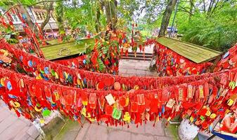 a chinese temple with many red and green ribbons hanging from the trees photo