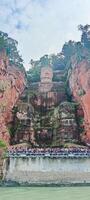 people are standing on the side of a cliff with a large statue photo