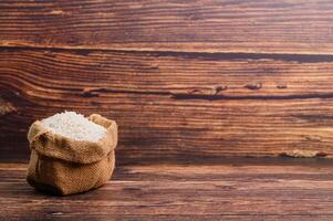 Rice in Burlap Bag on Wooden Table Background photo