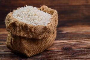 Fresh White Rice in Burlap Sack on Rustic Wooden Background photo