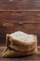 White Rice in Burlap Sack on Rustic Wooden Surface photo