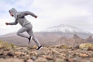 Active concentrated man running on stony ground photo