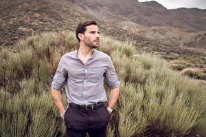 Confident man standing in valley covered with savanna grass photo