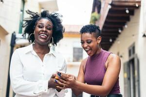 Happy women checking on mobile while walking in the city photo