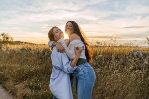two young women hugging on a field during sunset photo