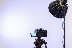 Back view camera on tripod and studio lights with blank screen backdrop photo