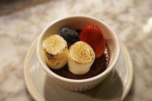 Close up bowl of grilled marshmallows and mixed berries topped on chocolate mousse photo