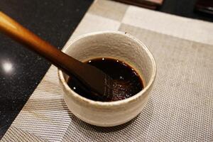 Close up wooden brush in sweet soy sauce bowl prepared for Sushi and Sashimi photo