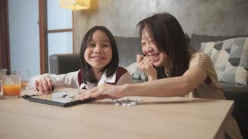 Mum, and kid fun playing Go, checkers board game on table in home living room together with love and cheerful, happy weekend relaxing hobby of Asian family, child and parent, concentrate and compete. photo