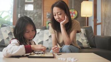 Asian family, mum, and kid fun playing Go, checkers board game on table in home living room together with love and cheerful, happy weekend relaxing hobby of child and parent, concentrate and strategy. photo