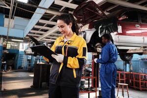 Hispanic female mechanic inspector, checklist service spare parts in maintenance work at a fix car garage station, professional engineer worker jobs in automotive and transportation industry business. photo