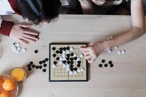 Close-up and top-view shots of GO, oriental checkers board game on wooden table are played by two players, leisure time hobby, strategy decision and tactic challenge with compete concentrate. photo