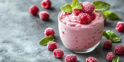 Delicious raspberry yogurt dessert garnished with mint leaves on a textured gray background photo