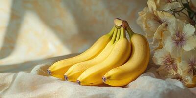 Fresh bananas arranged elegantly alongside delicate flowers on a soft fabric surface in warm light photo